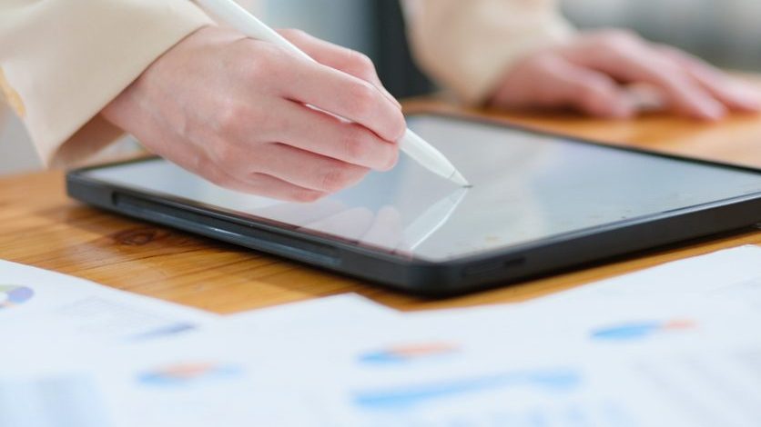 Close-up of hand signing electronic documents on a tablet with a digital pen for online workflows